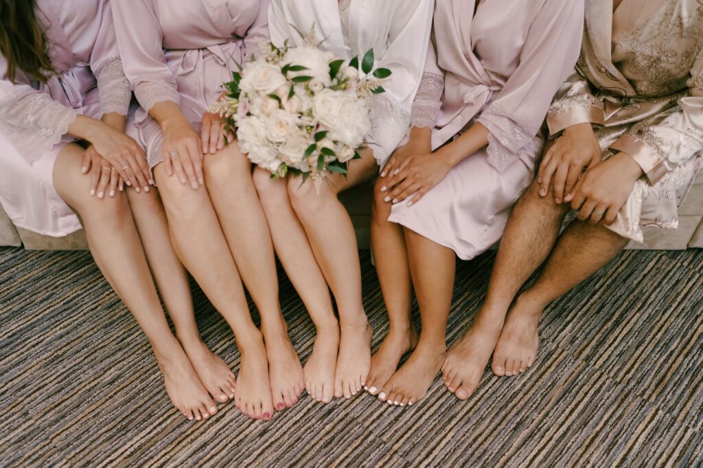 Bare feet of bridesmaids and bride with a bouquet of flowers